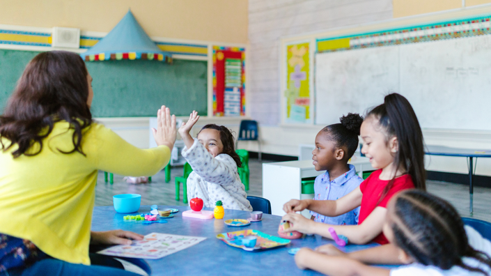 crianças em sala de aula interagindo com materiais sobre finanças, destacando a importância da educação financeira