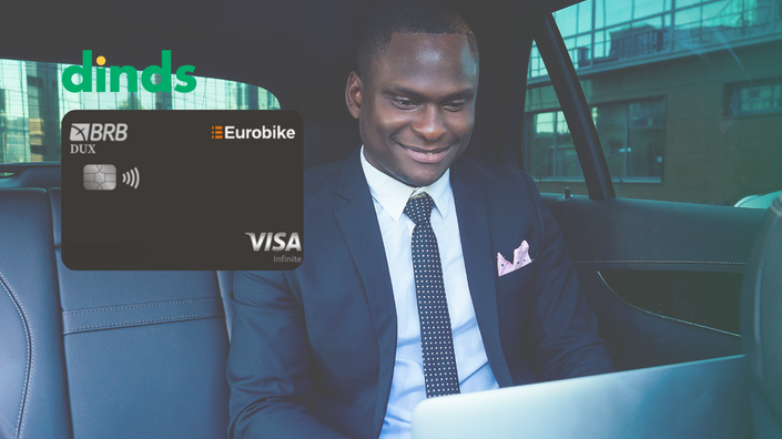 homem de terno olha feliz para a tela do notebook sentado no banco de trás de um carro com cartão dux eurobike ao lado