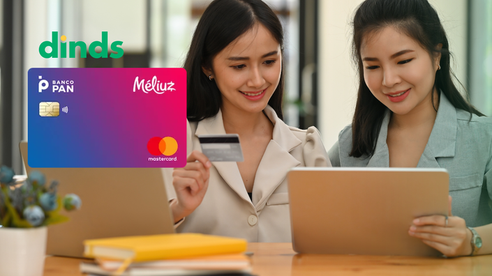 duas mulheres olham felizes o notebook e segurando cartão com cartão meliuz ao lado