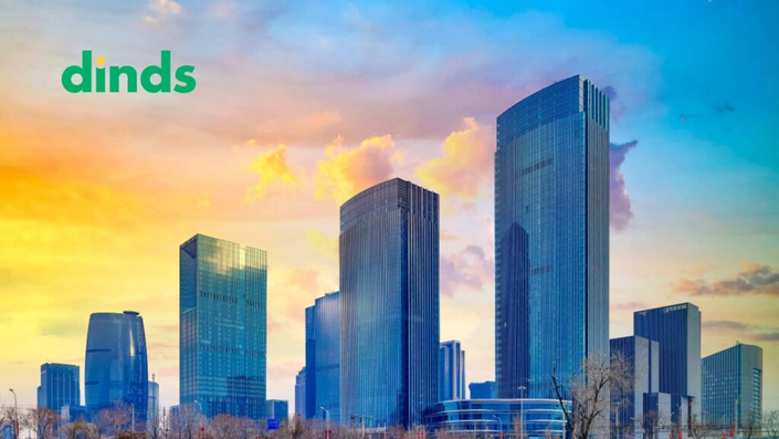 Vista urbana com arranha-céus e um canteiro de obras ao fundo, junto a uma casa à venda com uma placa, simbolizando oportunidades de investimento no mercado imobiliário.
