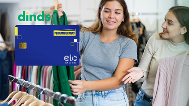 duas mulheres seguram roupa em loja de roupas com cartão pernambucanas ao lado