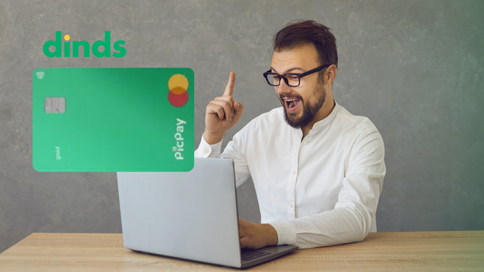 homem com face contente está com dedo indicador levantado e a outra mexendo no notebook com cartão pic pay gold ao lado