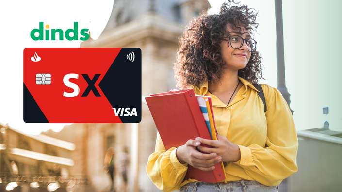 mullher sorri olhando para o horizonte segurando livros nos braços com cartão santander sx universitário