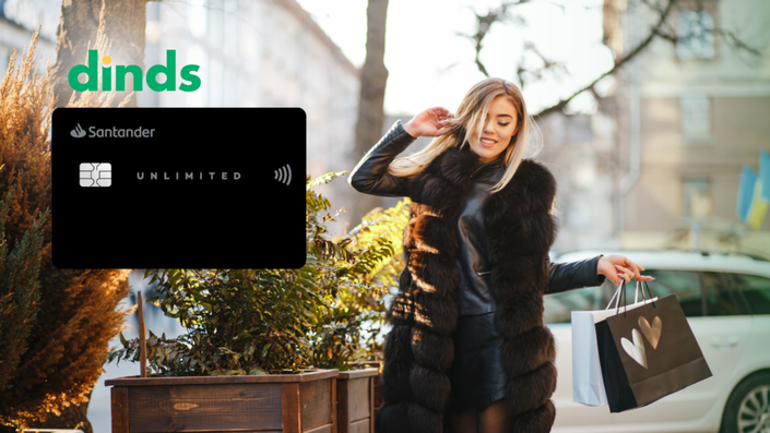 mulher caminha segurando sacola de compra com roupa preta com cartão santander unlimited ao lado