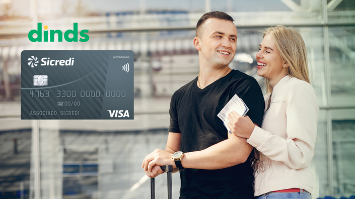casal sorri homem segura mala e mulher passagem em aeroporto com cartão sicredi internacional ao lado
