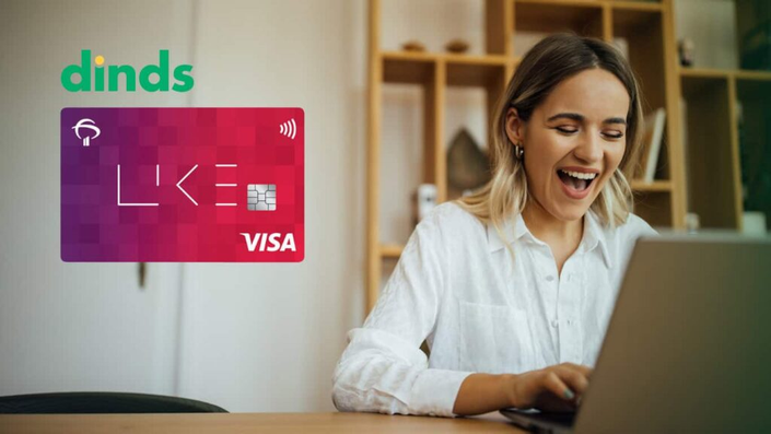 Mulher sorrindo com notebook e cartão de crédito bradesco like ao lado