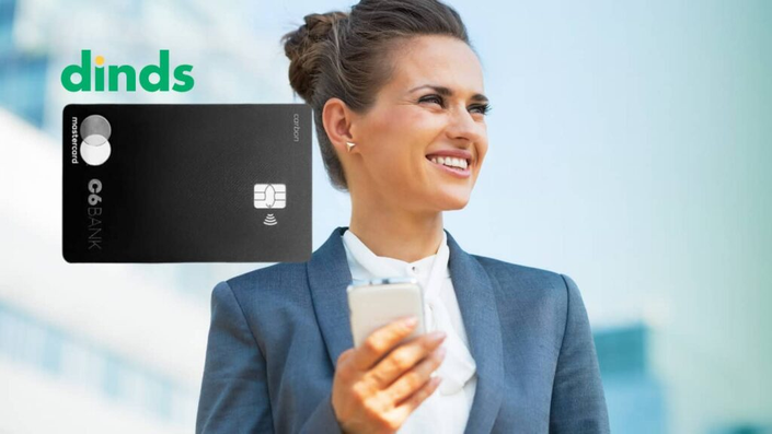 Mulher com celular na mão e cartão de débito c6 ao lado