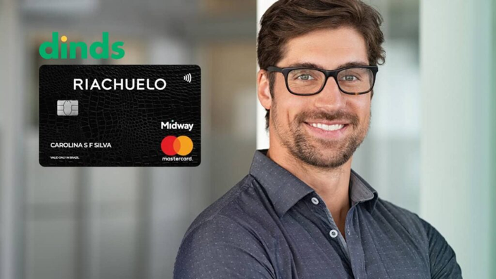 Homem sorrindo com cartão de crédito riachuelo ao lado
