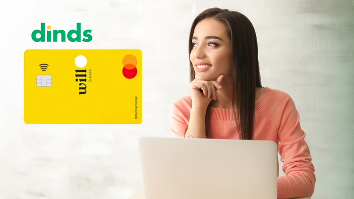 mulher sorri olhando para o horonte com notebook aberto com cartão will bank ao lado