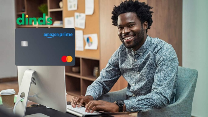 Homem sorrindo no computador com cartão de crédito amazon