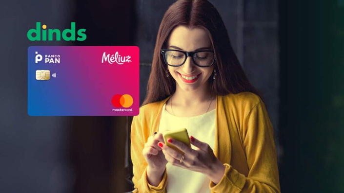 Mulher sorrindo com celular na mão e cartão Méliuz ao lado