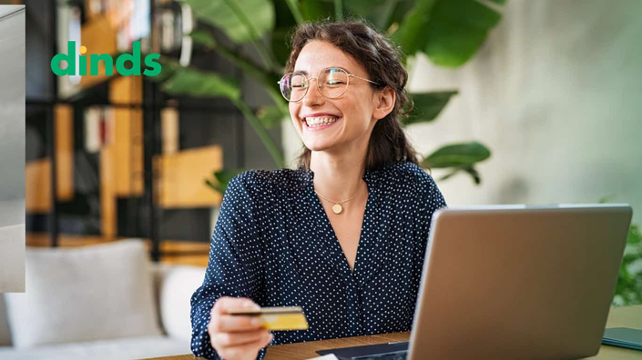 Mulher sorrindo com notebook e cartão na mão