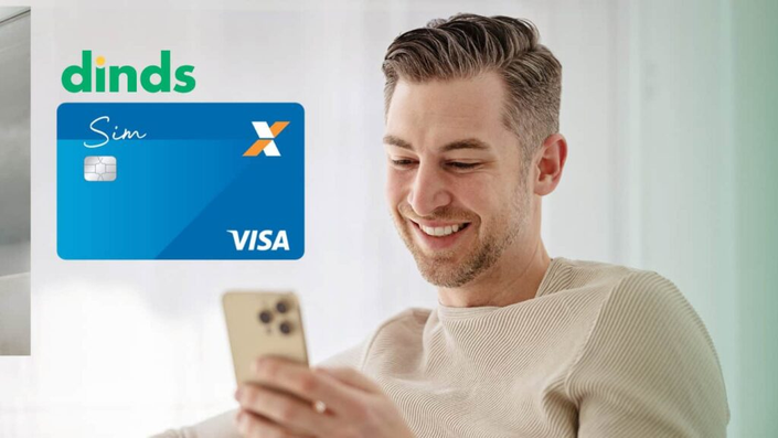 Homem no celular com cartão de crédito caixa sim ao lado