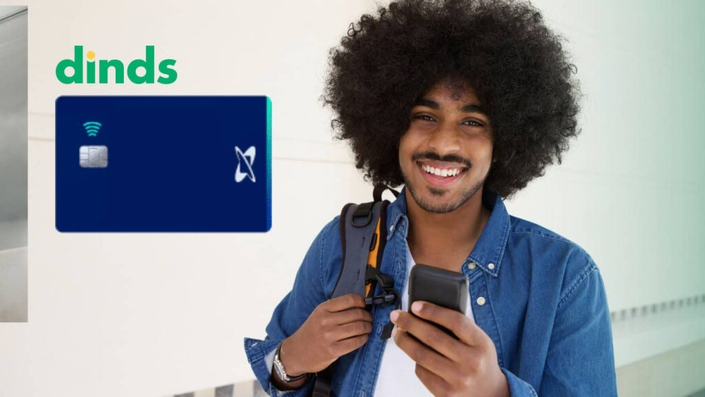Homem sorrindo com celular na mão e cartão credicard ao lado