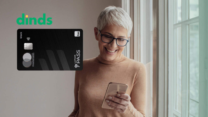 Mulher no celular com cartão itau latam pass ao lado