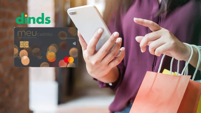 Mulher com celular na mão e cartão renner ao lado