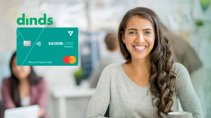 Mulher sorridente em ambiente de trabalho, ao lado da imagem do cartão Sicoobcard Clássico Mastercard e logo do Dinds.