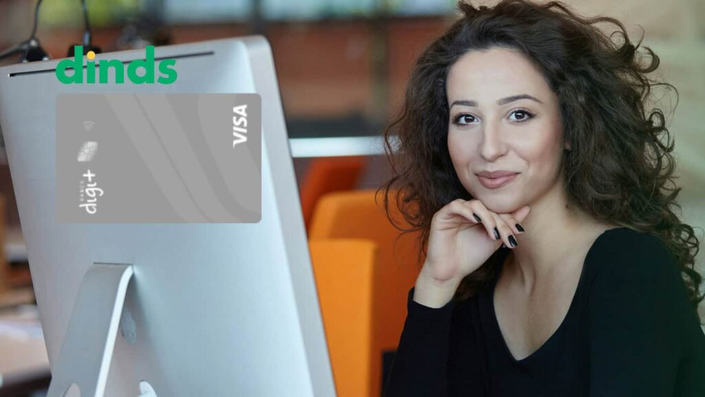 Mulher sorridente trabalhando em frente ao computador, ao lado da imagem do cartão Digi+ Visa Platinum e logo do Dinds.