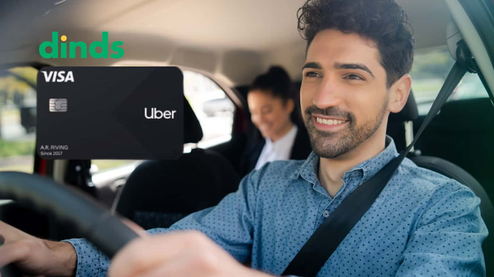Motorista sorridente dirigindo com passageira ao fundo, ao lado da imagem do cartão Uber Visa e logo do Dinds.